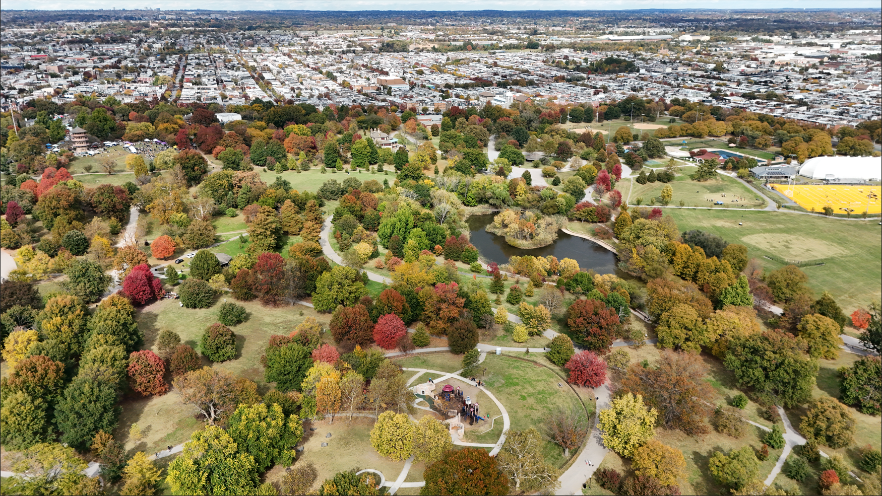 An aerial view of a park with a pond and a walking path.